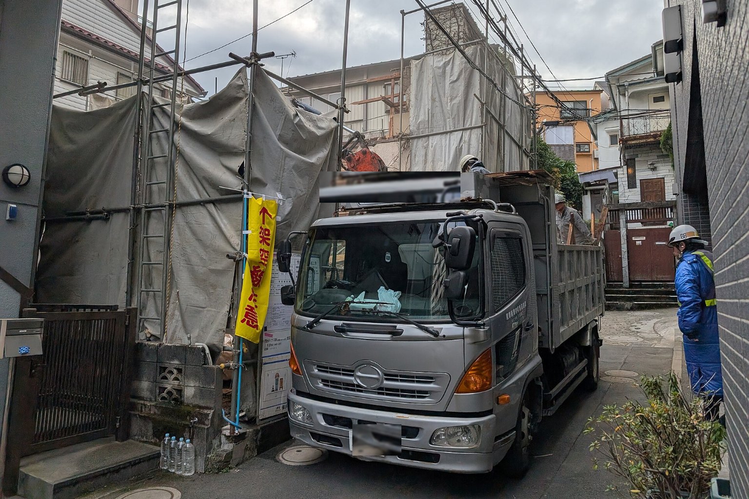 養生シートで囲い、シートの内側で解体作業を行う現場とダンプトラック